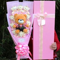 a person holding a large pink teddy bear and gift box