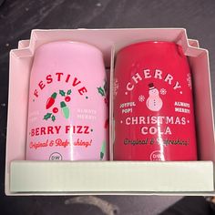 two red and pink christmas cups in a box on a counter top, one is empty