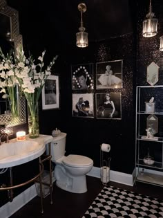 a bathroom decorated in black and white with pictures on the wall, toilet and sink