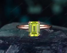 an emerald cut ring on top of a rock with the green stone in it's center