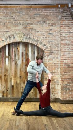 a man and woman are doing yoga in front of a brick wall with an arched doorway