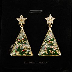 🎄 Celebrate the joy of the holiday season with these handmade resin earrings by Summer Garden, perfect for Christmas. Available in two festive designs--a wreath and a Christmas tree--these earrings are crafted to capture the magic of the season. Both styles feature delicate white petal accents embedded in shimmering resin with gold flakes, creating an elegant and joyful look. ✨ The wreath design resembles a classic holiday wreath, adorned with a charming gold-toned bow, while the tree design is Handmade Jewelry Earrings, Earrings Christmas, Gold Flakes, Wreath Designs, Tree Design, Classic Holiday, Resin Earrings, Handcrafted Earrings, Holiday Gathering