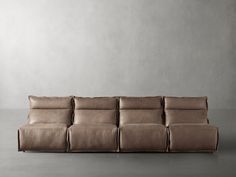 a leather couch sitting on top of a floor next to a white wall with no one in it