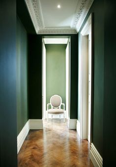 an empty room with green walls and a white chair