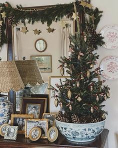 a decorated christmas tree sitting on top of a wooden table next to pictures and lamps