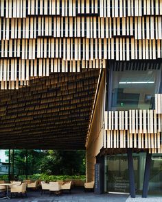 a building with wooden slats on the side and tables in front of it,