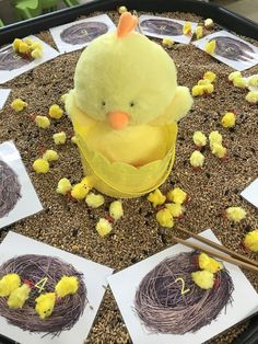 a yellow stuffed chicken sitting on top of a table next to eggs and straws