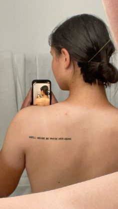 a woman taking a selfie with her cell phone in front of her back shoulder