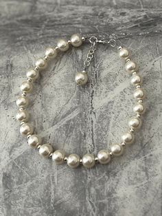 "Cream pearl anklet. Add a touch of elegance to your wardrobe with this timeless anklet. Handmade with love to elevate any look. 8mm faux pearls in a cream. The anklet is approximately 10\" and on a silver wire for strength. I have added an adjustable chain so can be altered to fit most. It closes with a lobster clasp. If you would like a different size making please just message me. Free shipping to UK buyers. I dispatch within 1-3 days but aim for next day postage with Royal Mail.  Presented on a gift card and wrapped beautifully in luxury tissue paper and a lovely organza bag to make the perfect gift.  Customer satisfaction is my main priority so if you are not completely in LOVE with your purchase, please let me know and you'll receive a stress free refund. Thank you for viewing. Pleas Elegant Pearl Chain Anklet For Party, Elegant Pearl Anklets For Party, Elegant Pearl Anklets With Pearl Chain, Elegant Pearl Chain Anklets, Elegant Pearl Anklets For Wedding, Elegant Pearl Chain Anklets For Wedding, Elegant Wedding Anklets With Pearl Chain, Elegant Wedding Pearl Chain Anklets, Elegant Adjustable Anklets With Pearl Charm