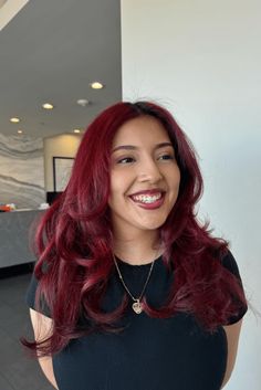 This vibrant deep cherry red hairstyle shows confidence and personal flair with its rich, shiny colors that reflect the light attractively. The hair flows in soft, full waves, giving the look a romantic and feminine vibe that's casually stylish. A gentle center-part allows the waves to surround the face evenly, adding a hint of - Click to see more of Turn Heads with These 28 Stunning Deep Cherry Red Hairstyles and follow us for more hairstyle ideas. // Photo Credit: Instagram @azulsbeauty Bright Red Hair On Brown Skin, Light Cherry Hair, Soft Red Hair, Red Hair Asian, Red Hair On Brown Skin, Deep Cherry Red Hair, Cherry Red Hair Color, Red Hair Pale Skin, Red Hair Color Shades