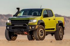 a yellow pick up truck parked in the desert