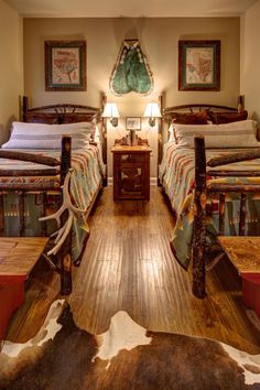 two beds in a room with wooden floors and cow hide rugs on the floor