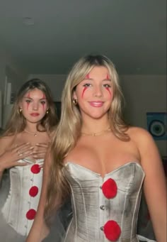 two women dressed in corsets with red pom poms on their cheeks