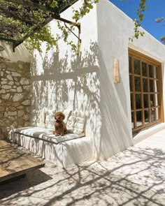 a teddy bear sitting on a white couch in front of a stone wall and tree