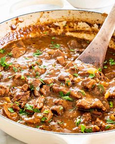 a large pot filled with meat and gravy on top of a white table