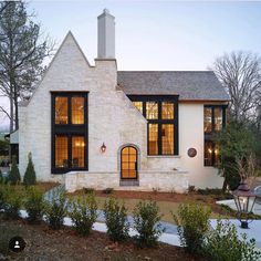 a white brick house with large windows at dusk