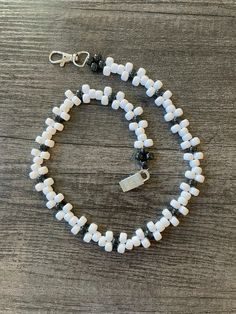 a white and black beaded necklace on a wooden table