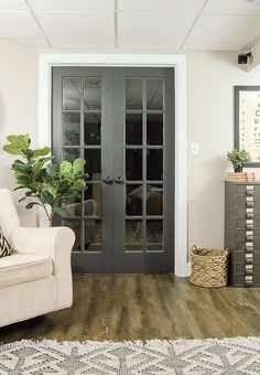 a white chair sitting in front of a black door with glass panels on the doors