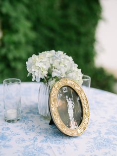 a vase with white flowers sitting on top of a table next to a glass cup