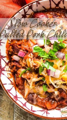 a bowl filled with chili and cheese on top of a wooden table