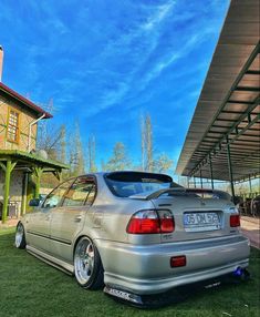 a silver car parked in front of a building on top of a lush green field