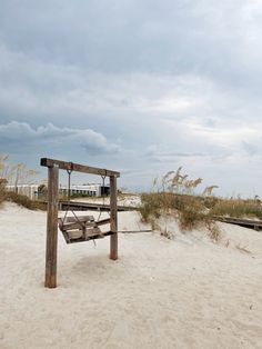 a wooden bench sitting on top of a sandy beach