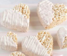 several heart shaped desserts with icing on a pink and white striped tablecloth