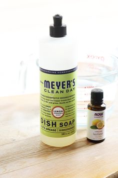 a bottle of dish soap next to a glass bowl with an orange and lemon liquid