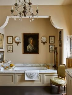 a fancy bathroom with chandelier, tub and paintings on the wall above it