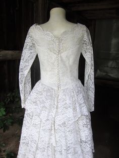 "This is a white lace and tulle full skirt wedding dress from the 1950's. The dress features a wide neckline with scalloped edges embellished with seed pearls and iridescent sequins. The sleeves are fitted and end in bridal points, opening with covered buttons and loops at the wrists. This dress opens down the back with covered buttons and loops and they are all there. The skirt is very full, with a multi tiered ruffled back. Under the lace layer is a full layer of tulle, and then an underskirt Vintage Lace Dress With Lace Bodice For Wedding, Vintage Fitted Petticoat For Wedding, Vintage Fitted Wedding Petticoat, Vintage Lace With Lace Bodice For Weddings, Vintage Lace Wedding Dress With Lace Bodice, Lace Ruffled Petticoat For Wedding, Ruffled Lace Petticoat For Wedding, Lace Petticoat With Ruffles For Wedding, Wedding Lace Petticoat With Ruffles