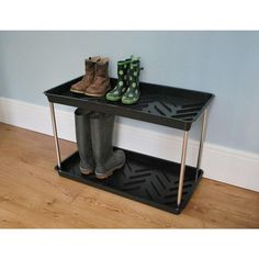 two pairs of boots sitting on top of a black shelf next to a wooden floor