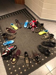 many pairs of shoes are arranged in a circle on the floor, with one shoelaced at the bottom