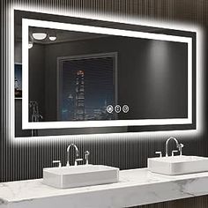 a bathroom with two sinks and a large mirror over it's counter top that is illuminated by lights