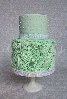 a three tiered green wedding cake with polka dots and roses on the bottom layer