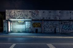 an empty parking lot with graffiti on the wall and door to another building at night