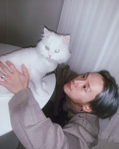 a woman is petting a white cat on the table