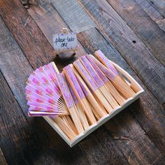 a wooden box filled with lots of pink and white matchsticks on top of a wooden table