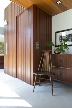 a room with wood paneling and a chair in the corner next to a mirror