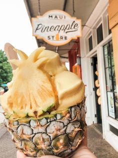 a person holding up a pineapple in front of a store