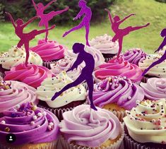 cupcakes with purple frosting and pink icing are displayed on a table