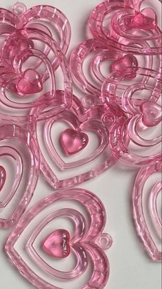 pink glass hearts are arranged on a white surface