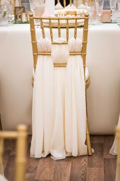 the chairs are covered in white chiffon and gold trims, along with champagne glasses