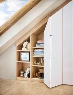 an attic bedroom with white cupboards and wooden flooring on the bottom half of the room