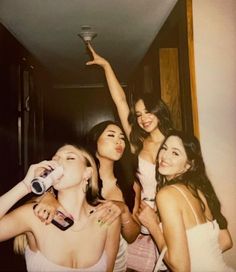 four young women are posing for the camera and drinking from bottles in front of them