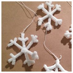 three snowflakes are hanging from string on the table, and one is made out of yarn