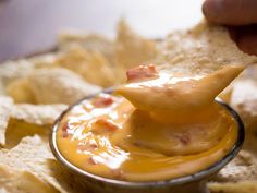 a person dipping cheese on top of tortilla chips