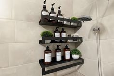 three shelves holding bottles and soaps in a bathroom