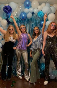 four girls posing in front of balloons and streamers