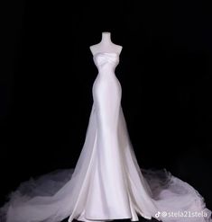 a white wedding dress on display in front of a black background