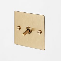 a light switch with two brass knobs on the side of a white cabinet door